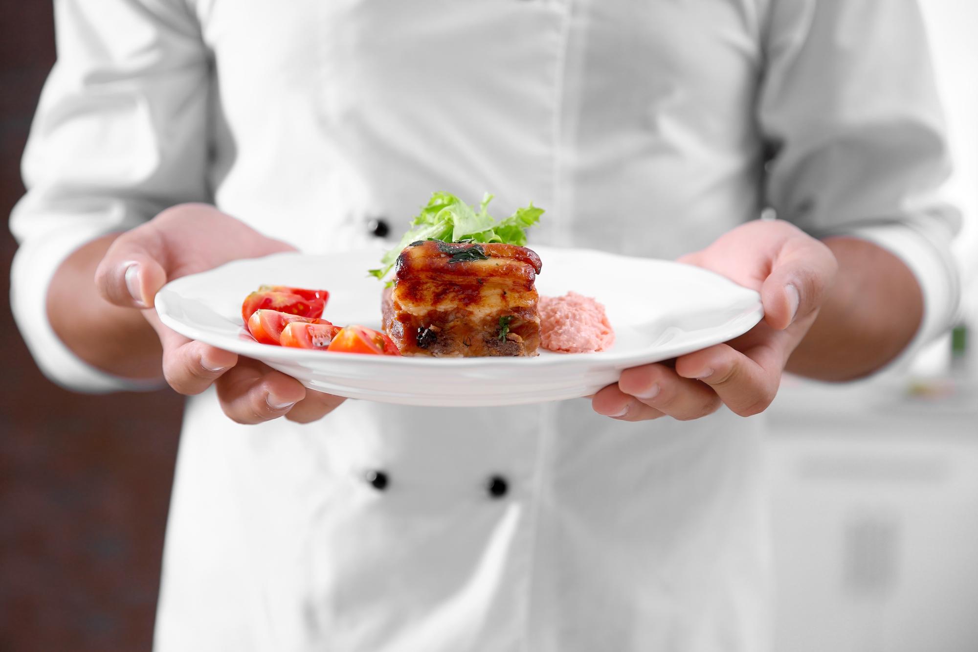 Chef arranging plated tasting menu on wooden table